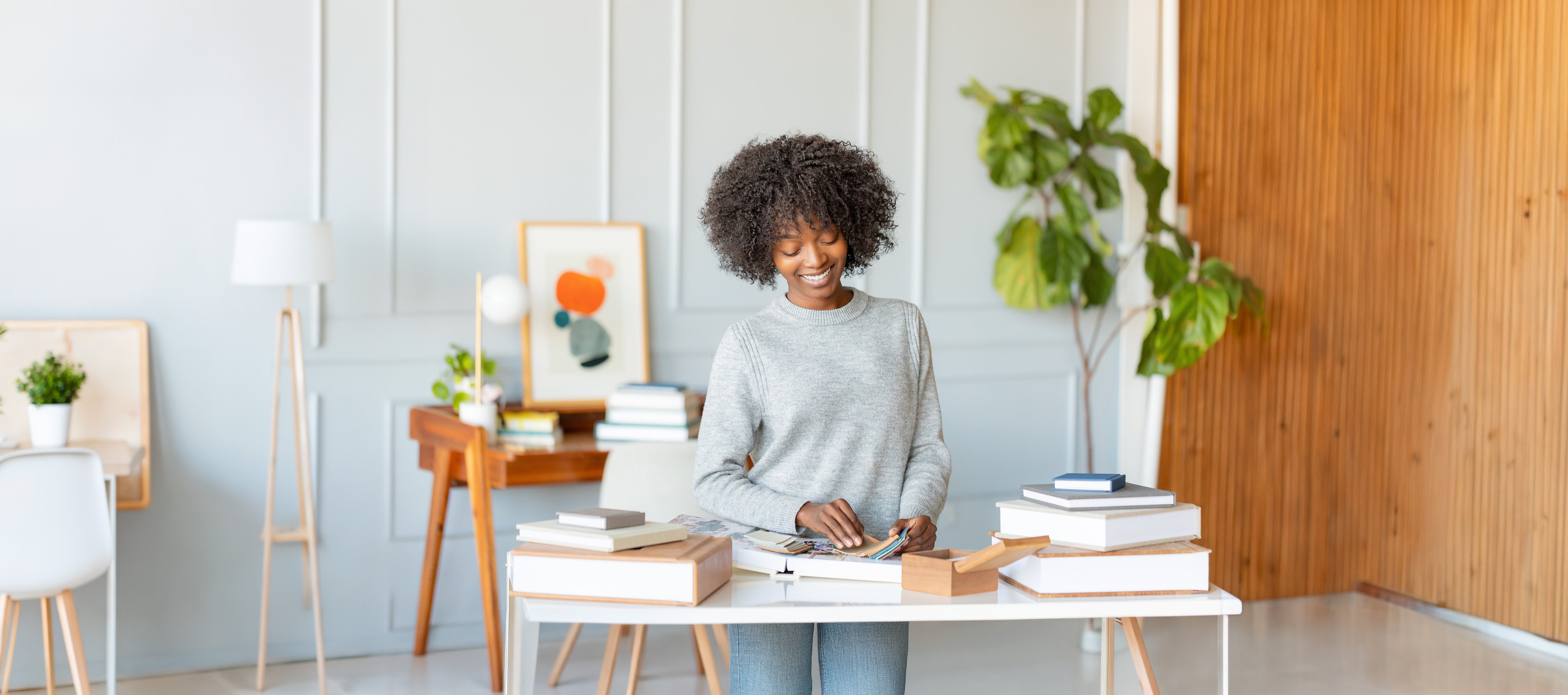 Woman sitting at a desk in a modern office space with books and plants.